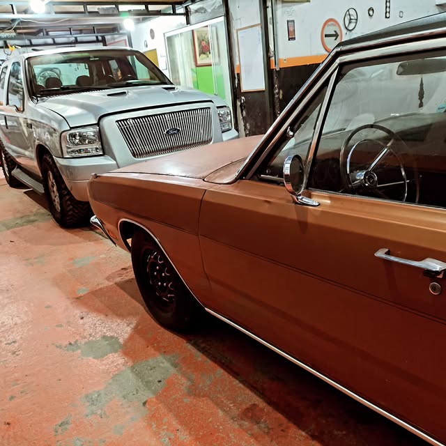 Interior da oficina com picape e carro clássico lado a lado