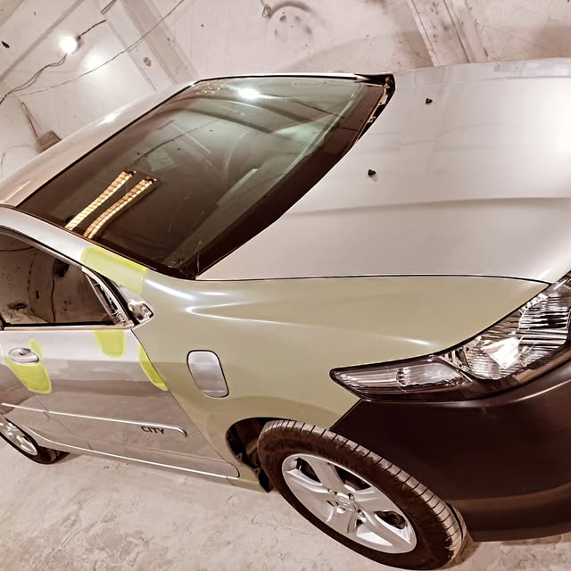 Carro preparado com fita crepe dentro da cabine de pintura da oficina